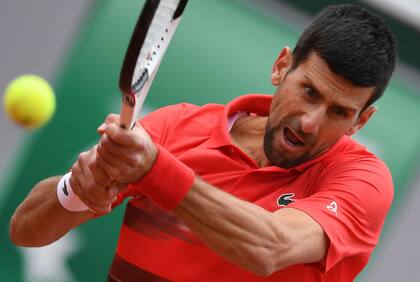 El serbio Novak Djokovic juega una devolución de revés al argentino Diego Schwartzman durante su partido individual masculino el día ocho del torneo de tenis Roland-Garros Open en la Court Suzanne Lenglen en París el 29 de mayo de 2022. (Foto de JULIEN DE ROSA / AFP)