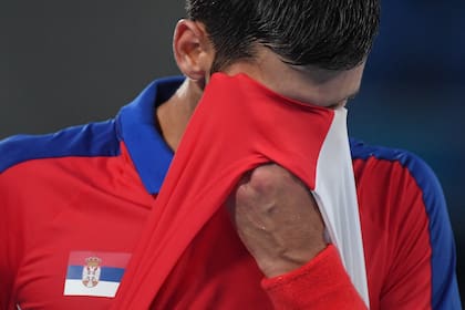 El serbio Novak Djokovic se limpia la cara mientras compite contra el alemán Alexander Zverev durante el partido de tenis de la semifinal masculina individual