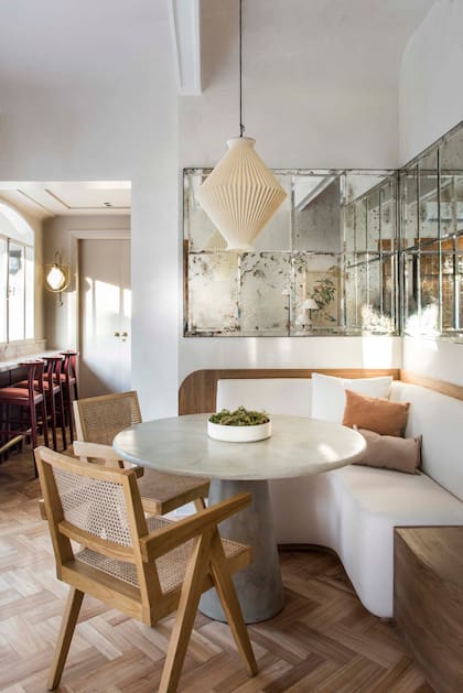 El sillón amurado, diseño de Estudio Método con género de Tienda Mayor, recorre living y comedor. En este extremo funciona como rinconero, junto a la mesa redonda. almohadones (Good Luck Casa). Espejo envejecido (Estudio Método).