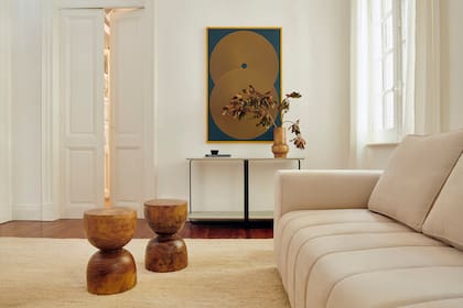 El sillón, la alfombra de yute (Rug it) y los tochos, que funcionan tanto en verano como en invierno, se visten de temporada de la mano de un arreglo con ramas secas a tono con la obra de Pioppo Estudio.