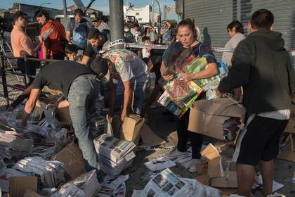 Varias personas se llevan los diarios y revistas que llevaba el camión