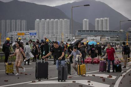Los pasajeros se dirigen al Aeropuerto Internacional de Hong Kong a pie porque las carreteras están bloqueadas