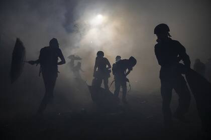 Los manifestantes son alcanzado por los gases intentan protegerse en la universidad de Hong Kong