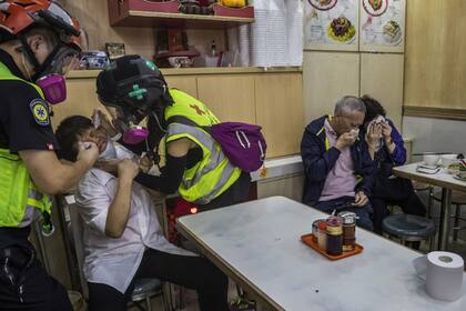 El empleado de un restaurante es auxiliado por los médicos mientras los clientes se cubren la cara con pañuelos