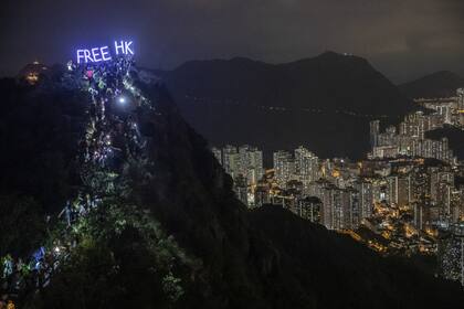 Cientos de manifestantes suben a la cima de Lion Rock mientras sostienen un cartel iluminado con la leyenda "Free HK"