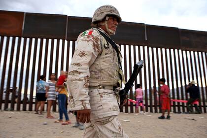 Un soldado mexicano camina cerca de las familias que juegan en la zona fronteriza