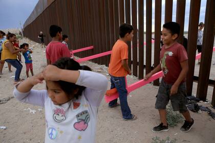 Varios niños juegan en el subibaja instalado en Ciudad Juárez, en el muro fronterizo que separa México de los Estados Unidos