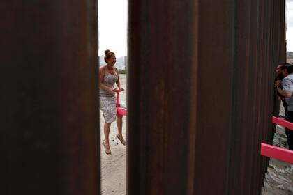 Una mujer estadounidense sonríe mientras charla con un hombre del lado mexicano