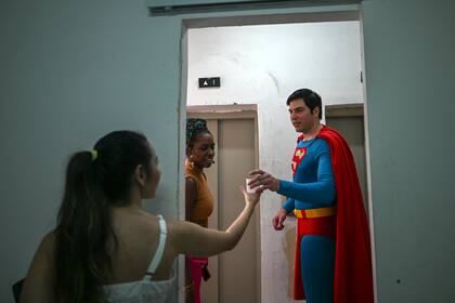 El Superman brasileño recibe un vaso de agua de su novia Helenise Santos durante una visita a la Asociación de Padres y Amigos de Personas Neurodivergentes (APAE-RIO) en el barrio de Tijuca en Río de Janeiro
