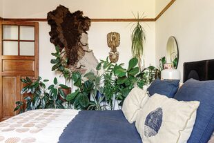 El tapiz de lana natural en tonos de marrón (Vera Somlo) y las plantas le dan al dormitorio un aire exuberante y silvestre.