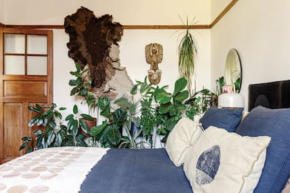 El tapiz de lana natural en tonos de marrón (Vera Somlo) y las plantas le dan al dormitorio un aire exuberante y silvestre.