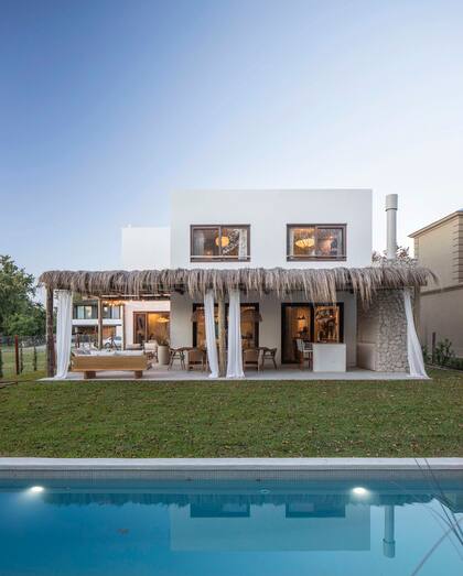 El techo de la galería con palma y cortinas de gasa, puro estilo de playa. Para que la pileta mantuviera esa onda natual, la revistieron con venecitas claras (Murvi).