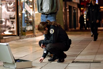 Una oficial de la Policía Federal realiza pericias tras el tiroteo del barrio de Belgrano