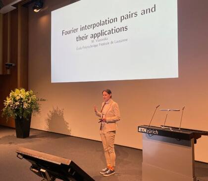 El título de la conferencia de Viazovska, que organizó el departamento de matemáticas del ETH Zürich, se tituló: Pares de interpolación de Fourier y sus aplicaciones