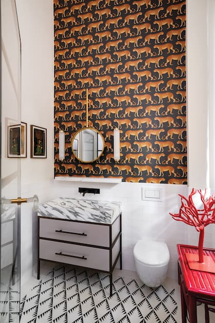 El toilette, con piso calcáreo, mueble con gruesa mesada de mármol (IR), y el impactante empapelado ‘Leopard Walk’ (Cole & Son).