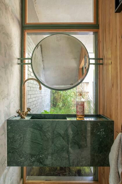 El toilette ubicado junto al tiene un paño de vidrio sobre el que parecen flotar un espejo biselado de dos caras y la bacha de mármol ‘Ubatuba’ (ambos de Arquitectura Goldenhorn).