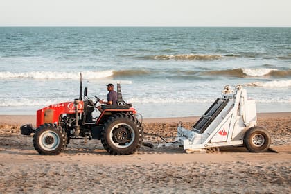 El tractor de Santander limpia la playa al atardecer e imprime la huella con el logo del banco