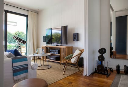 El último piso fue lo primero que se intervino: se hizo el gimnasio con espejos de puntas redondeadas y un panel corredizo que permite independizarlo del living. Mueble de TV y mesas a medida (todo de Salazar Estudio).