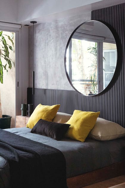 El varillado, tan usado últimamente, cobra originalidad con un gran espejo circular en el ángulo del corte en L (Estudio Cántaro-Bardó). Ropa de cama (Lote Propio).