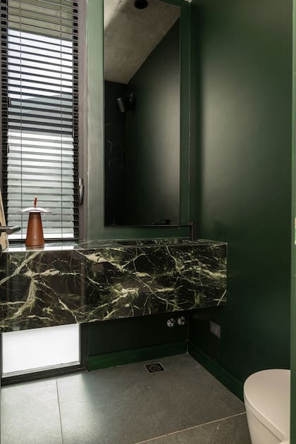 El verde del exterior entra al toilet gracias a las paredes pintadas en 'Ramo de laurel' satinado (Albalatex). Mesada 'Veria Green' (De Stefano por Marmolería Progettit Marmolería). Grifería negra (Peirano), persianas (Modo Cortinas).