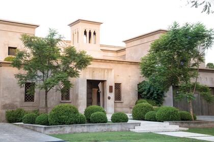 El verde intenso de las bochas de buxus y de los árboles que flanquean la entrada logran un efecto de contraste con el color tierra pálido de las paredes de la casa. Ningún elemento compite ni pasa desapercibido en esta fachada.