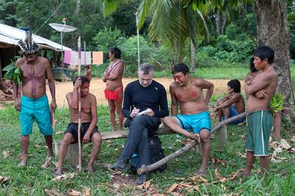 El veterano corresponsal extranjero Dom Phillips (centro) toma notas mientras habla con indígenas en Aldeia Maloca Papiú, estado de Roraima, Brasil, el 15 de noviembre de 2019. (Photo by Joao LAET / AFP)