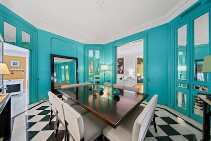 El vibrante turquesa del comedor proporciona un contraste que complementa la sala.