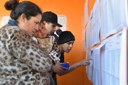 Varias personas mirando el padrón en una escuela de Moreno