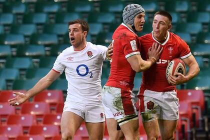El galés Jonathan Davies felicita a Josh Adams por su try contra Inglaterra, que protesta por una controvertida decisión del referí francés Pascal Gaüzère; el Dragón ganó por 40-24 y los ingleses ya no tienen chances de ser campeones.