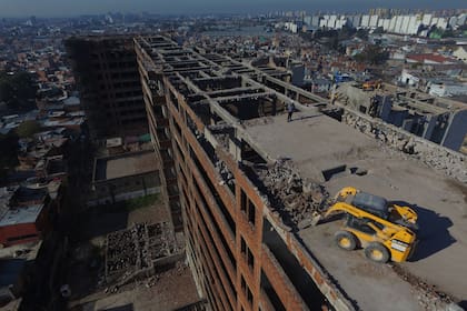 Dos pequeñas máquinas retroexcavadoras a 25 metros de altura, hacen un trabajo de demolición artesanal en la estructura que durante años fue el símbolo del abandono y la marginalidad