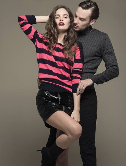 Ella: suéter de lana rayado (Wanama), minifalda de charol con cierre (Comité Apparel), botas de neoprene (Sarkany). Él: suéter de lana y pantalón chino de gabardina (Rochas).
