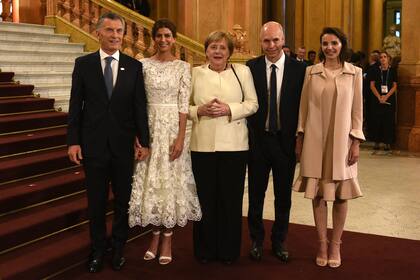 Ellos con traje. Merkel, sobria con un equipo en dos tonos. Bárbara Diez con vestido de multivolados y saco. Juliana, radiante con su vestido diseño de Javier Saiach