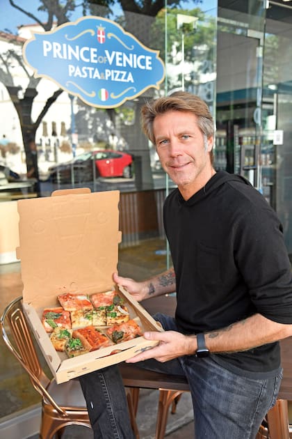 Emanuele Filiberto de Saboya posa en el frente de su restaurante Prince of Venice, ubicado en Westwood, Los Ángeles, y muestra orgulloso uno de los productos estrella del local, la vera pizza italiana.