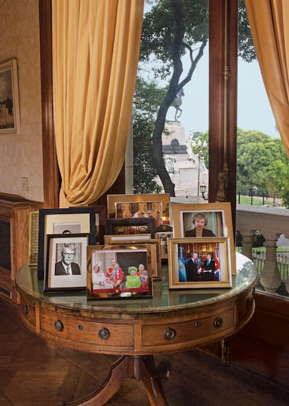 La mesa con los retratos de la familia real. En primer plano, una foto de un encuentro con el presidente Mauricio Macri y un retrato de la primera ministra Theresa May.