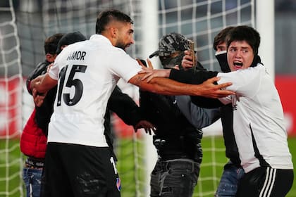 Emiliano Amor, de Colo Colo de Chile, enfrenta a un grupo de hinchas que invadieron la cancha durante el encuentro con Fortaleza de Brasil