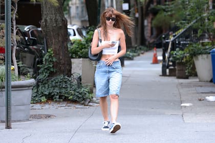 Emily Ratajkowski chequea su teléfono mientras camina por las calles de su ciudad. La modelo pasó casi desapercibida con un top strapless blanco, unas bermudas de jean anchas y unas zapatillas Vans negras
