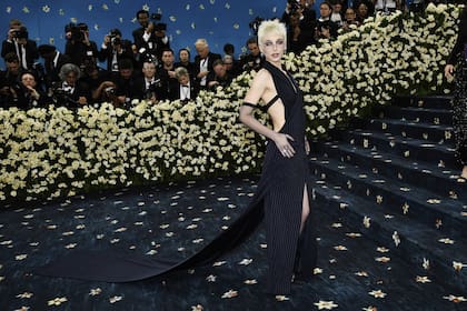 Emma Chamberlain, una de las primeras en llegar a la gala del Met, con un vestido cut-out de raya diplomática, tajo central en la falda, cola y guantes semitransparentes