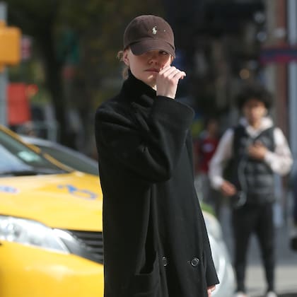 Emma Stone pasa por Starbucks para tomar un café helado en la ciudad de Nueva York; Emma se esconde debajo de una gorra de béisbol de Ralph Lauren y lleva un abrigo cruzado con zuecos

