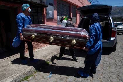 Empleados de la funeraria Los Cirios cargan el féretro de un hombre que falleció por Covid-19, en el sur de Quito, el 11 de agosto de 2020