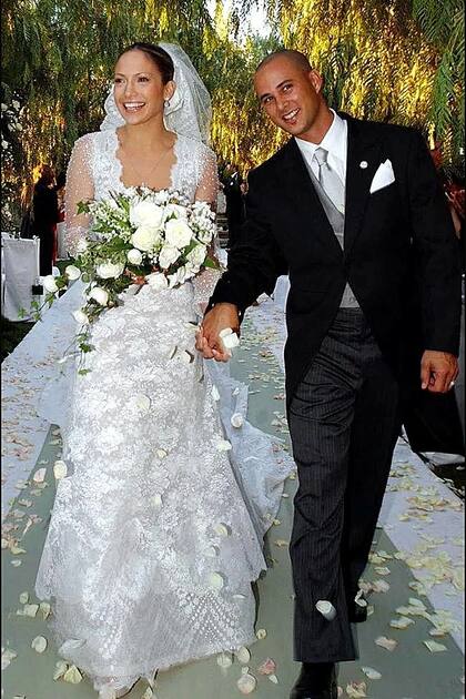 En busca de un diseño romántico, Jennifer Lopez eligió a Valentino para su boda con el bailarín Cris Judd en 2001. El diseñador creó im vestido de color marfil con encaje Chantilly y mangas transparentes