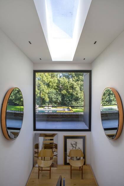 En casa de Lara Bernasconi y Federico Álvarez Castillo, el descanso de la escalera con espectacular vista se ambientó con espejos enfrentados y un dúo de sillas (Santiago del Campo)