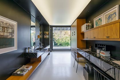En el ambiente que funciona como tocador, vestidor y espacio de trabajo, pintaron los muros de negro y usaron mármol ‘Marquina’ para las mesadas, el mismo material elegido para revestir el baño.