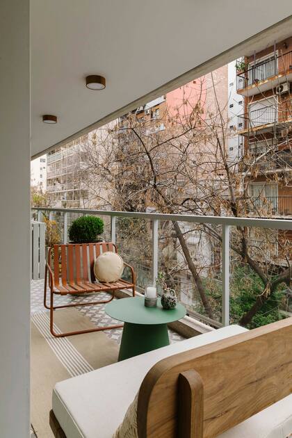 En el balcón, un pequeño living que repite el terracota y el verde vistos en el interior diario. Mesa (Cúmulo). Silla (El Yeite). Banco diseñado por Camila Monge y realizado por Taller Ferro. Macetas y plantas (MS Paisajismo). Alfombra (Rug It). Plafones de madera (KOLOR Iluminación)