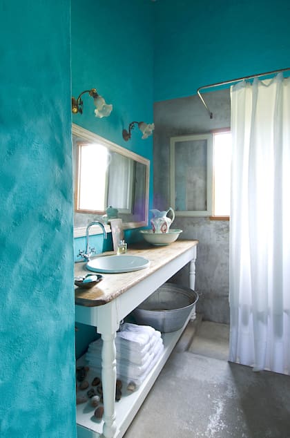 En el baño de invitados, se salió de la gama neutra con un contraste fresco de turquesa y blanco. El mueble del lavatorio se hizo con una pieza de la cocina original
