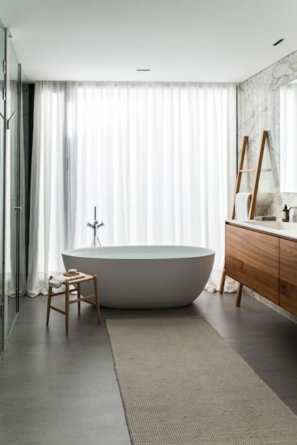 En el baño de la master suite, alfombra de fibras naturales (Monoccino), bañadera exenta y cortinas de algodón.