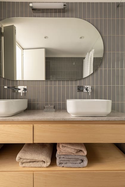 En el baño de la pareja, doble bacha y elegantes cerámicos grises.