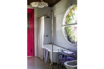 En el baño, la puerta es fucsia con un componente flúo para que brille más. Ventana redonda y lámpara fileteada por Luis Zorz.