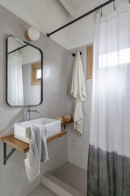 En el baño, piso y revestimiento de cemento alisado (Miracema). Mesada de madera con bacha de apoyo (Rocca), grifería (FV), toalla de mano (Lote Propio). Espejo (Za Mobiliario Industrial), lámpara (Dimm), cortina (Maru Bardó).