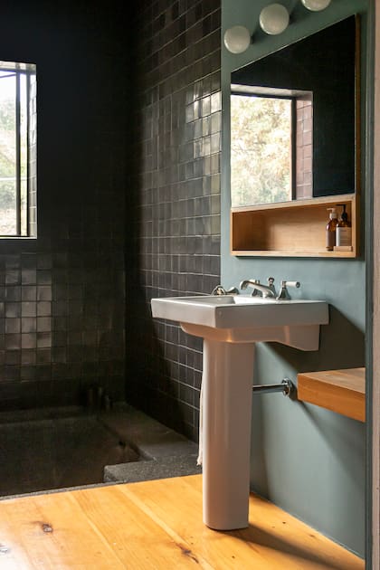 En el baño principal, una bañadera de roca volcánica se acompañó de talaveras negras: un marco teatral para la ventana que mira al jardín.