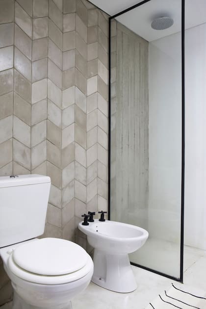 En el baño, revestimiento ‘Estocolmo’ gris (Bará) y pared de ducha en microcemento de tono similar. Griferías negro mate (Piazza).